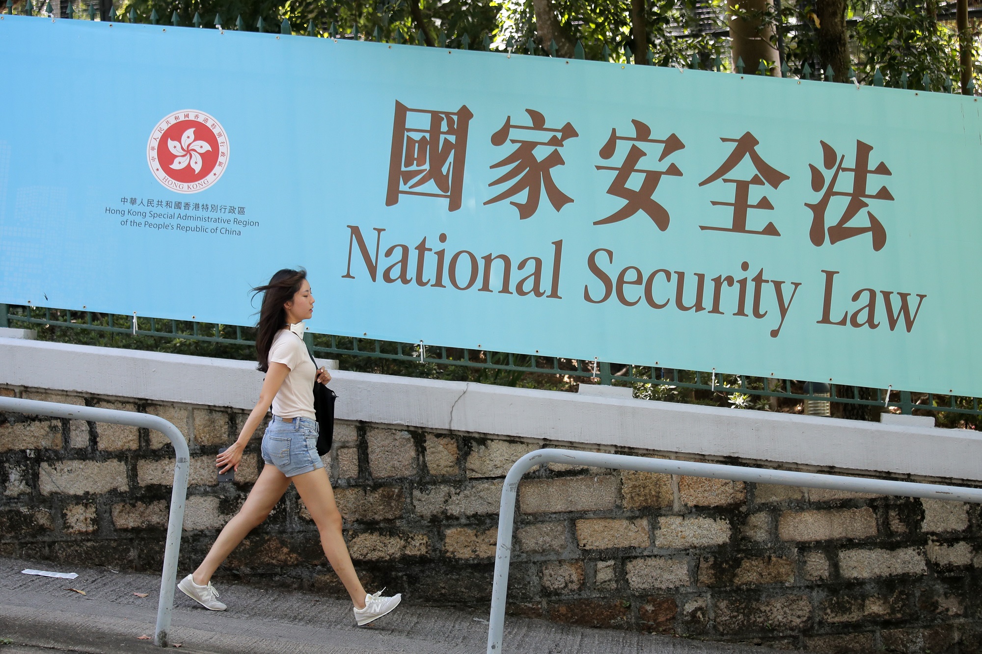 Một người đi bộ qua khu vực trưng biểu ngữ cổ động cho Luật An ninh Quốc gia ở Hong Kong, ngày 30/6/2020. Ảnh: AP.